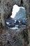 Frame view through a hole in a rock. Waves bounces against coast rocks