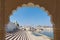 Framed view from archway at Pushkar, Rajasthan, India. Temples, buildings and ghats on the holy water of the lake at sunset.