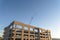 Framework of an unfinished building with a towering crane in the background