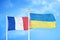 France and Ukraine two flags on flagpoles and blue cloudy sky