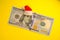 Franklin President in a red Santa Claus hat on a 100 US dollar bill on a bright yellow background. The concept of the cost of