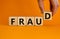Fraud symbol. Concept word fraud on wooden cubes on a beautiful orange table.