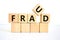 Fraud symbol. The concept word `fraud` on wooden cubes on a beautiful white table. White background. Business and fraud concept
