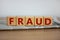 Fraud symbol. Wooden cubes placed on a newspaper. The word \\\'fraud\\\'.