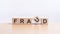 Fraud - words from wooden blocks with letters, of inform brief concept, light yellow background