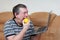 Freak eats lemon while holding a laptop while sitting on the couch