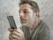 Freak and weird looking man using mobile phone watching something online in sick intense face expression in internet and social