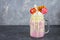 Freakshake from pink smoothie, cream. Monstershake with lollipops, waffles and marshmallow. Extreme milkshake in a Mason jar. Gray