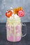 Freakshake from pink smoothie, cream. Monstershake with lollipops, waffles and marshmallow. Extreme milkshake in a Mason jar. Gray