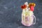 Freakshake from pink smoothie, cream. Monstershake with lollipops, waffles and marshmallow. Extreme milkshake in a Mason jar. Gray