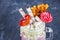 Freakshake from pink smoothie, cream. Monstershake with lollipops, waffles and marshmallow. Extreme milkshake in a Mason jar. Gray