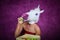 Freaky young woman in comical mask stands on the purple background