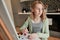 Freckled girl looking away while painting in her home