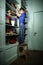 Freckled red-haired little boy searching book on bookcase