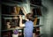 Freckled red-haired little boy searching book on bookcase