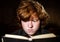 Freckled red-haired teenage boy reading book, education concept