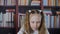 Freckled schoolgirl writing on bookshelf background. Portrait smiling student girl writing homework in classroom on
