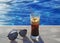 Freddo espresso coffee with sunglasses in front of a pool - cold coffee - summer vacation