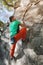 A free aged male climber hangs on a rock wall in a forest in the mountains. Mature Sports Concept