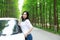 Free carelss happy woman stand by a white car on a road in forest