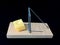 Free cheese in a mousetrap on a black background. Wooden trap with bait and mechanism for rats and mice