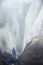 A free climber with an ice ax stands at the foot of the Great Glacier next to an epic crack in the fog in the mountains