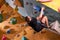 Free climber young man climbing on practical wall indoor, bouldering, side view