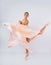 Free flight. Graceful classic ballerina dancing on white studio background. Pastel beige dress cloth. The grace, artist, movement