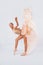 Free flight. Graceful classic ballerina dancing on white studio background. Pastel beige dress cloth. The grace, artist, movement