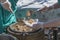 Free food field kitchen. Female hands put portions of buckwheat porridge from an army thermos into plates