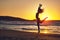 Free at last. Silhouette of an energetic woman jumping on the beach at sunset.