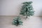 Free-standing pieces of artificial Christmas tree against a white wall. Installation of a tree for the new year