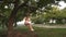 Free young girl swinging on a rope swinging on an oak branch. healthy child swinging on swing in park in sun. Girl loves