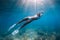 Freediver glides over sandy sea with white fins. Slim woman free diver in ocean