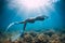 Freediver glides over sandy sea with white fins. Slim woman free diver in ocean