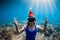 Freediver woman with Christmas cap posing underwater in blue sea. Christmas holiday