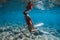 Freediver woman in swimsuit look at camera underwater in blue ocean