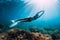 Freediver young woman with white fins glides undersea with sun rays. Freediving in transparent sea