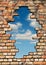 Freedom - A hole in the brick wall with cloudy sky in the background, portrait format