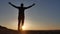 Freedom. Man stands on a cliff sunset silhouette hand in the sides lifestyle