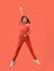 Freedom in moving. Pretty young woman jumping against coral background