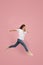 Freedom in moving. Pretty young woman jumping against pink background