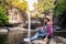 Freedom traveler woman alone sitting waterfall front on stone with bag and hat and a beautiful nature.