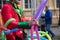 A freelance clown creating balloon animals and different shapes at outdoor festival in city center.