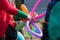 A freelance clown creating balloon animals and different shapes at outdoor festival in city center.