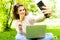 Freelance concept. charming girl with a laptop and ice cream makes a selfie while sitting on the grass in the park