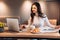 Freelance student woman using laptop while sitting at home. Young woman sitting in kitchen and working online on laptop