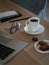 Freelancer desktop with laptop, notes, glasses, coffee cup and cookies