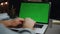 Freelancer hands texting greenscreen laptop dark room closeup. Man arms typing