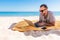 Freelancer, happy successful businessman in sunglasses on vocation with laptop on the beach under umbrella